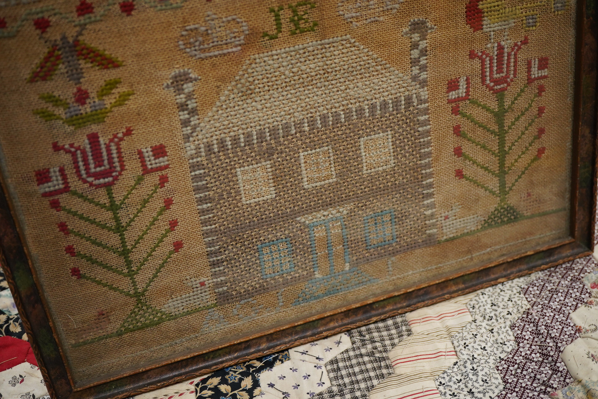 A 19th century alphabet cross stitch sampler, worked with a large house motif - 41cm x 29cm, together with a 19th century unfinished cotton patch worked central panel. Condition - the sampler has some stains but the thre